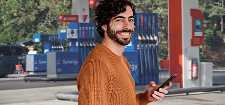 Eine Person hält ein Telefon an einer Esso-Tankstelle